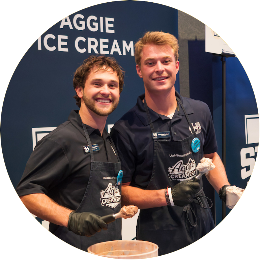Two student ambassadors scooping Aggie Ice Cream at an event.